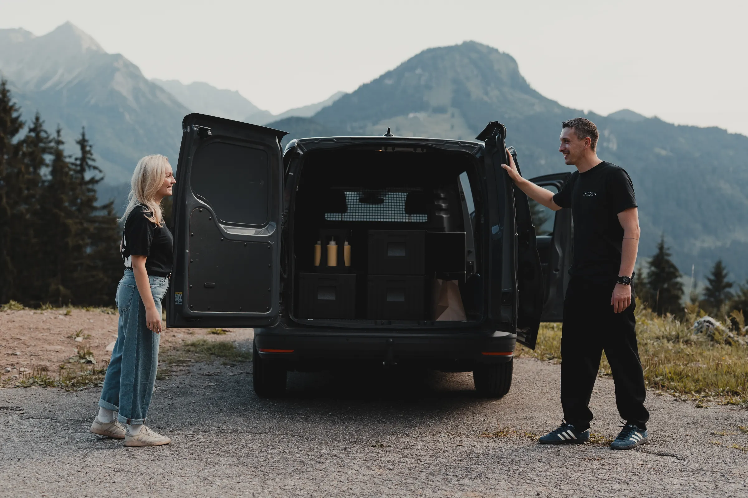 Zwei Personen schließen die Türen eines Lieferwagens mit Cateringboxen