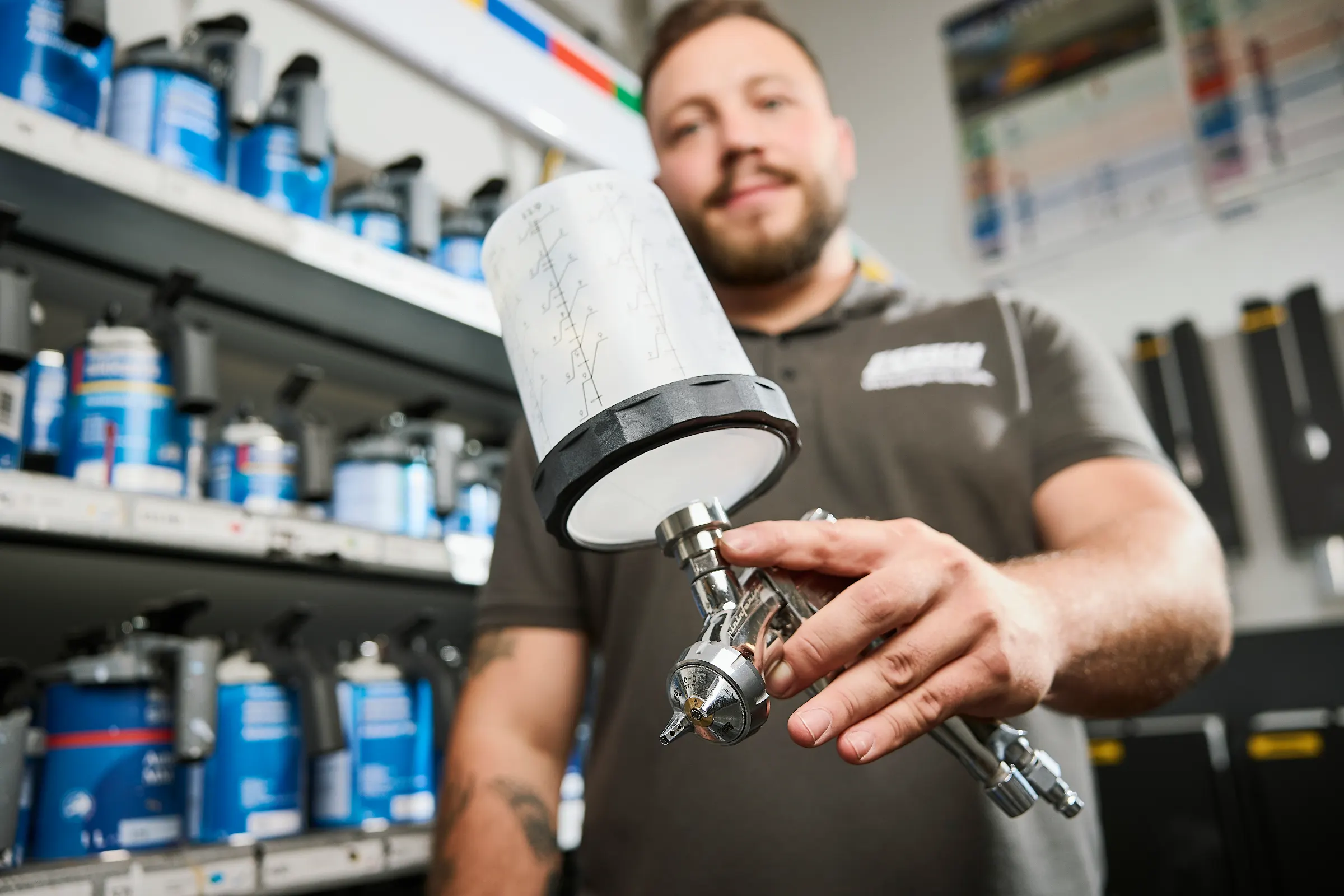 Lackmischung im Autohaus Fersch: Mitarbeiter mit Lackbecher vor dem Farbregal im Mischraum